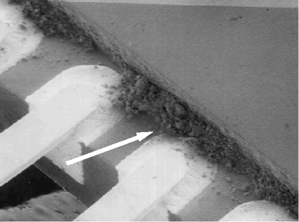 SEM image showing contamination bridging two leads on a package. (Courtesy DM Data).